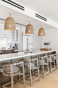 You'll love cooking in this stunning kitchen with its spacious marble island, modern appliances, and warm woven pendant lights creating a welcoming atmosphere.