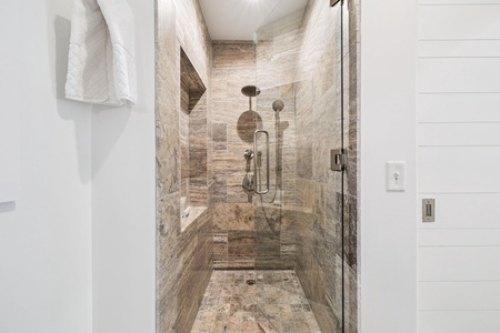 Step into your luxurious stone-tiled shower with dual rainfall heads and handheld sprayer for the ultimate spa experience.