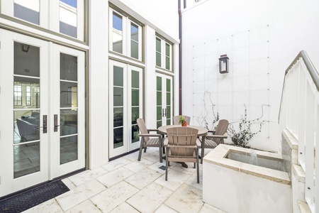 Step onto your private stone patio where weathered teak chairs invite morning coffee and evening conversations in this peaceful courtyard retreat.