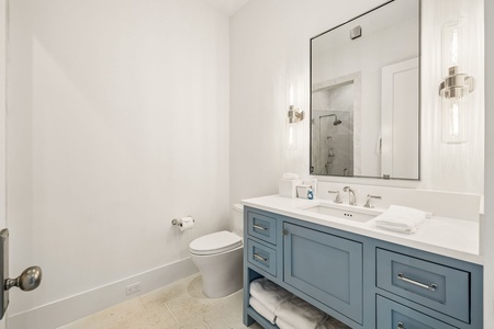 Step into this modern bathroom featuring a serene blue vanity with ample storage, crisp white countertops, and elegant lighting—perfectly designed for your daily refresh.