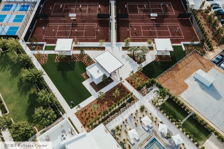 Aerial view of the resort's recreational facilities including tennis courts, swimming pool, and landscaped grounds surrounded by lush gardens.