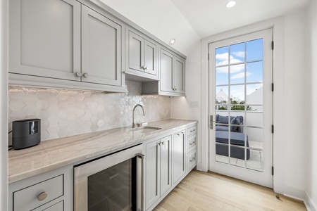 Your private kitchenette features elegant marble counters, stylish hexagonal tile backsplash, and opens to a peaceful outdoor terrace through French doors.