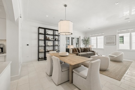 Relax in your bright, open-concept living space where natural light streams through expansive windows, highlighting elegant furnishings and tasteful decor. The dining area flows seamlessly into a cozy lounge, perfect for gathering.