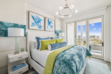 Wake to coastal elegance in your bright bedroom, where ocean-inspired blues meet fresh greens and natural light streams through your private balcony doors.