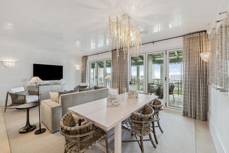 Step into your elegant open-concept living space where modern luxury meets coastal comfort, featuring stunning chandeliers and expansive balcony access.