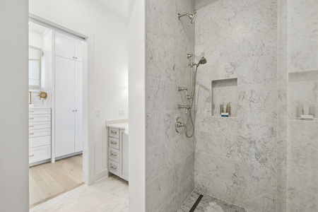 Step into this luxurious spa-style shower with gleaming marble tiles, rainfall showerhead, and built-in nooks for your essentials—your private haven awaits.
