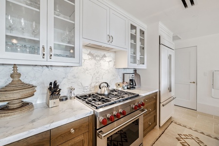 Cook like a chef in your elegant kitchen with marble counters, professional-grade appliances, and gleaming white cabinetry.