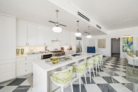 Cook and gather in this stunning modern kitchen featuring sleek white cabinetry, spacious island seating, and designer touches throughout your stay.
