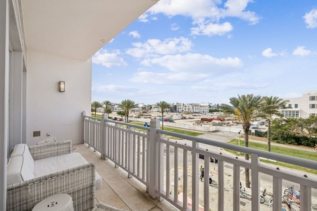 Spacious balcony with comfortable seating overlooking palm-lined streets and neighborhood views.