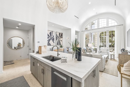 Step into this airy, light-filled space where your vacation home blends kitchen, living, and outdoor access seamlessly. Elegant archways, modern fixtures, and lush greenery create a welcoming retreat for your memorable stay.