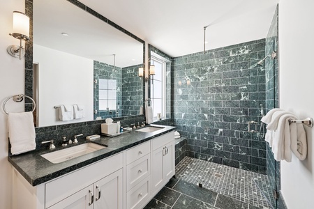 Unwind in this luxurious marble bathroom featuring elegant green stone tiles and pristine white fixtures for your ultimate relaxation.