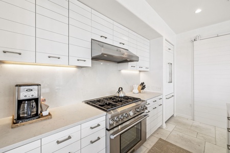 Cook your favorite meals in this sleek, modern kitchen with stainless steel appliances and pristine white cabinetry.
