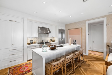 Gather around this bright, open kitchen where you can prep meals together at the spacious island. White cabinetry, warm wood floors, and modern appliances create an inviting space for your mornings and evenings.