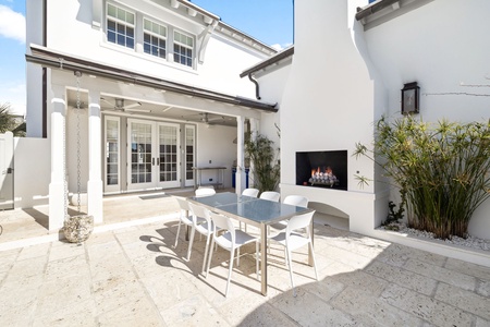 Your private courtyard features elegant dining space with modern fireplace, surrounded by lush tropical plants for intimate outdoor meals.