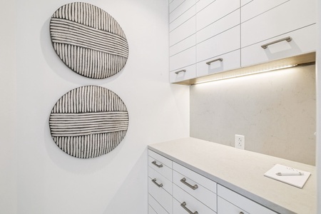 Your modern kitchen features sleek white cabinetry, elegant countertops, and stylish artwork that creates a sophisticated cooking space.