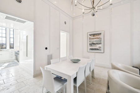 Gather around your elegant white dining table beneath a stunning chandelier, where memorable meals become cherished moments in this bright, sophisticated space.