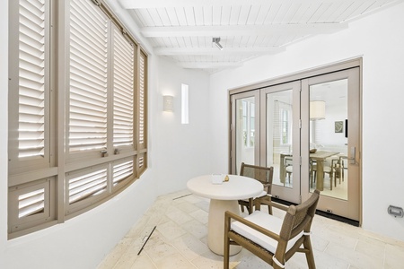 Settle into this serene, sun-drenched sitting area where elegant louvered shutters frame your private retreat, and soft natural light invites you to unwind with a morning coffee or evening read.