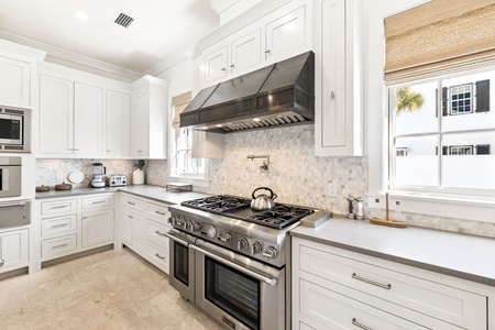 Cook like a chef in your pristine kitchen with professional-grade appliances and elegant white cabinetry.