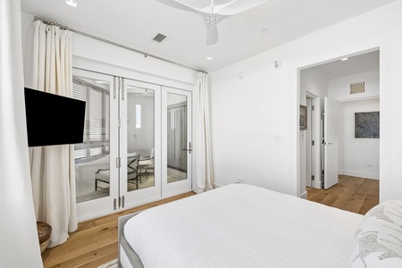 Slip into this bright, airy bedroom where crisp white linens meet warm wood floors. Your private balcony awaits through French doors, while the ceiling fan keeps you comfortable year-round.