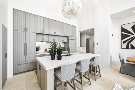 Gather at the sleek marble island where modern design meets effortless functionality. The floor-to-ceiling cabinetry and soft under-cabinet lighting create an inviting space for your morning coffee or meal prep.