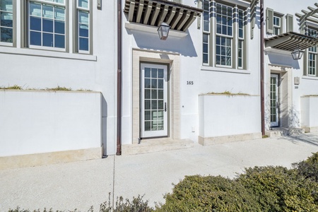 Modern townhome entrance featuring clean white architecture with decorative shutters and balconies, unit 165 offers contemporary style.