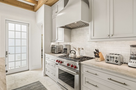 This bright kitchen blends rustic charm with modern convenience, featuring exposed wood beams, sleek appliances, and ample counter space for preparing your favorite meals during your stay.