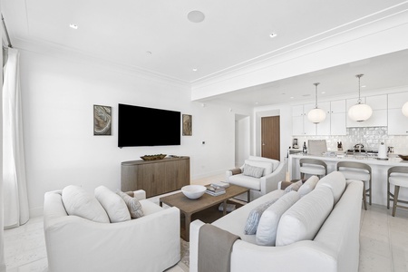 Sink into plush white sofas in your open-concept living area, where elegant finishes and a fully equipped kitchen invite you to unwind and enjoy leisurely evenings together.