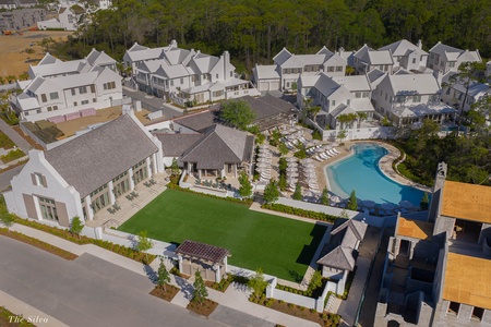 Aerial view of an upscale residential community featuring modern architecture, mature landscaping, and resort-style amenities including a sparkling swimming pool.