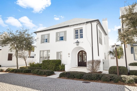 Elegant white facade with traditional shutters and arched entrance creates a welcoming arrival experience in this charming neighborhood setting.
