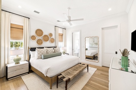 Unwind in your serene master bedroom with coastal charm—woven wall art and tropical touches create your perfect retreat.