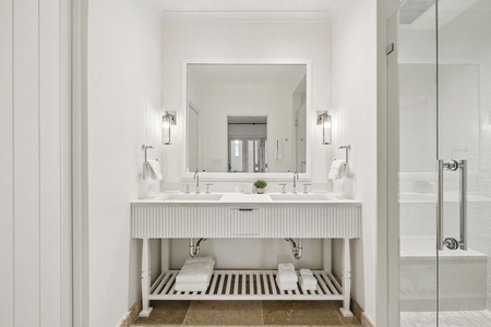 Your spa-like bathroom features gleaming white marble, dual sinks, soft ambient lighting, and a walk-in glass shower—refined luxury meets effortless comfort.
