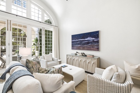 Unwind in this sun-drenched living room with soaring ceilings and floor-to-ceiling windows that flood the space with natural light and garden views.
