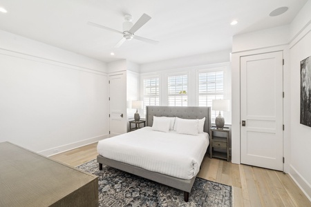 Drift into peaceful sleep in this serene bedroom with plush bedding, warm wood floors, and gentle natural light streaming through shuttered windows.