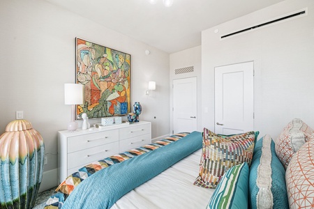 Sink into your vibrant bedroom sanctuary where colorful artwork meets crisp comfort, perfectly cooled by modern climate control.