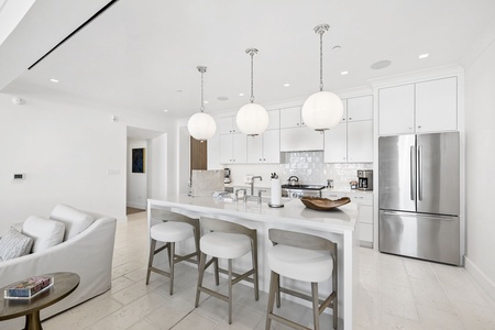 Your sleek white kitchen island with modern pendant lighting is perfect for sipping morning coffee, prepping meals, or gathering with friends over drinks.