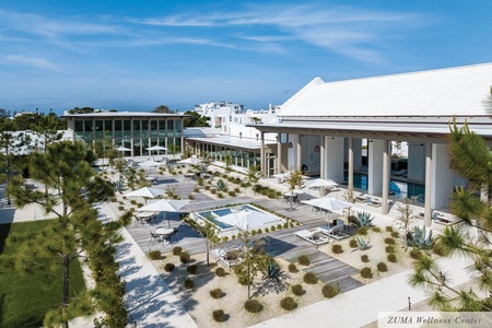 Modern wellness resort with pristine pools, tropical gardens, and contemporary architecture set against clear blue skies.
