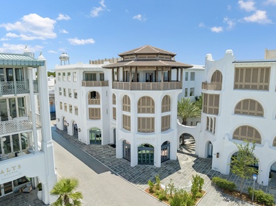 Mediterranean-inspired property featuring pristine white architecture with distinctive arched windows, shaded outdoor courtyards, and a signature rooftop pavilion, all set in a charming coastal community.