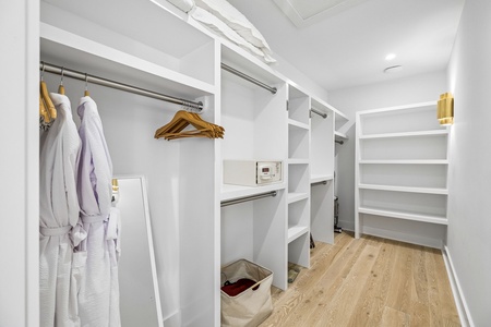 Your spacious walk-in closet offers ample storage with multiple hanging rods, open shelving, and a personal safe for your valuables, plus cozy robes waiting for you.