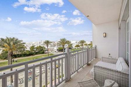 Relax on your private balcony with comfortable wicker seating while taking in views of palm trees and neighborhood streets.