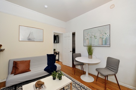 Relax in your bright living room with cozy seating and dining area, perfectly styled for intimate meals and quiet evenings.