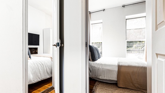 Wake up to natural light streaming through large windows, creating a peaceful retreat with comfortable bedding and warm hardwood floors.