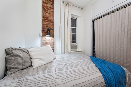 Rest peacefully in your cozy bedroom where exposed brick meets modern comfort, complete with blackout curtains for perfect sleep.