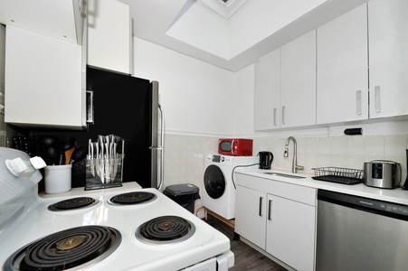Bright white kitchen with skylight offers everything you need to cook your favorite meals with modern appliances and ample counter space.