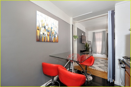 Gather around your modern glass dining table with vibrant red chairs, where colorful artwork brightens your open-concept living space.