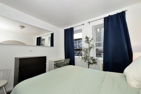Wake up refreshed in your bright bedroom with natural light streaming through elegant navy curtains and charming city views.