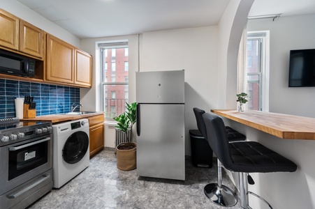 Your fully-equipped kitchen features modern appliances, stylish blue subway tile, and a breakfast bar perfect for morning coffee or casual meals.