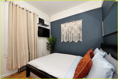 Relax in your stylish bedroom featuring a plush bed, striking blue accent wall, and modern amenities for your comfort.