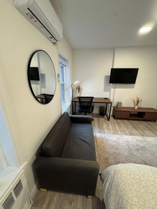 Unwind in your modern retreat with cozy seating, workspace, and entertainment center - perfect for both relaxation and productivity.