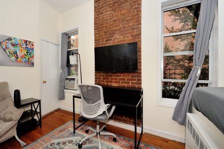 Your stylish workspace features a sleek desk against exposed brick, perfect for remote work or planning your city adventures.