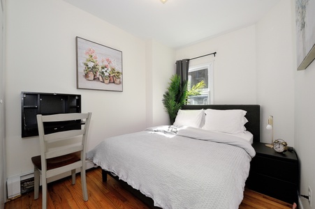 Unwind in your cozy bedroom featuring crisp linens, warm hardwood floors, and thoughtful touches like fresh greenery.